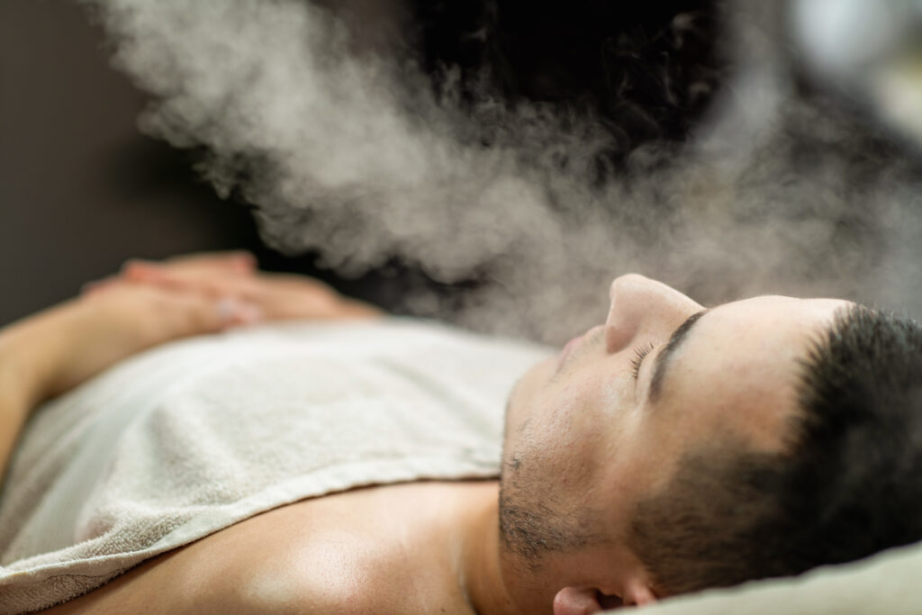 Man enjoying a beauty treatment with an ozone facial steamer at a professional beauty center, designed to cleanse, hydrate, and rejuvenate facial skin for a refreshed and healthy appearance.
